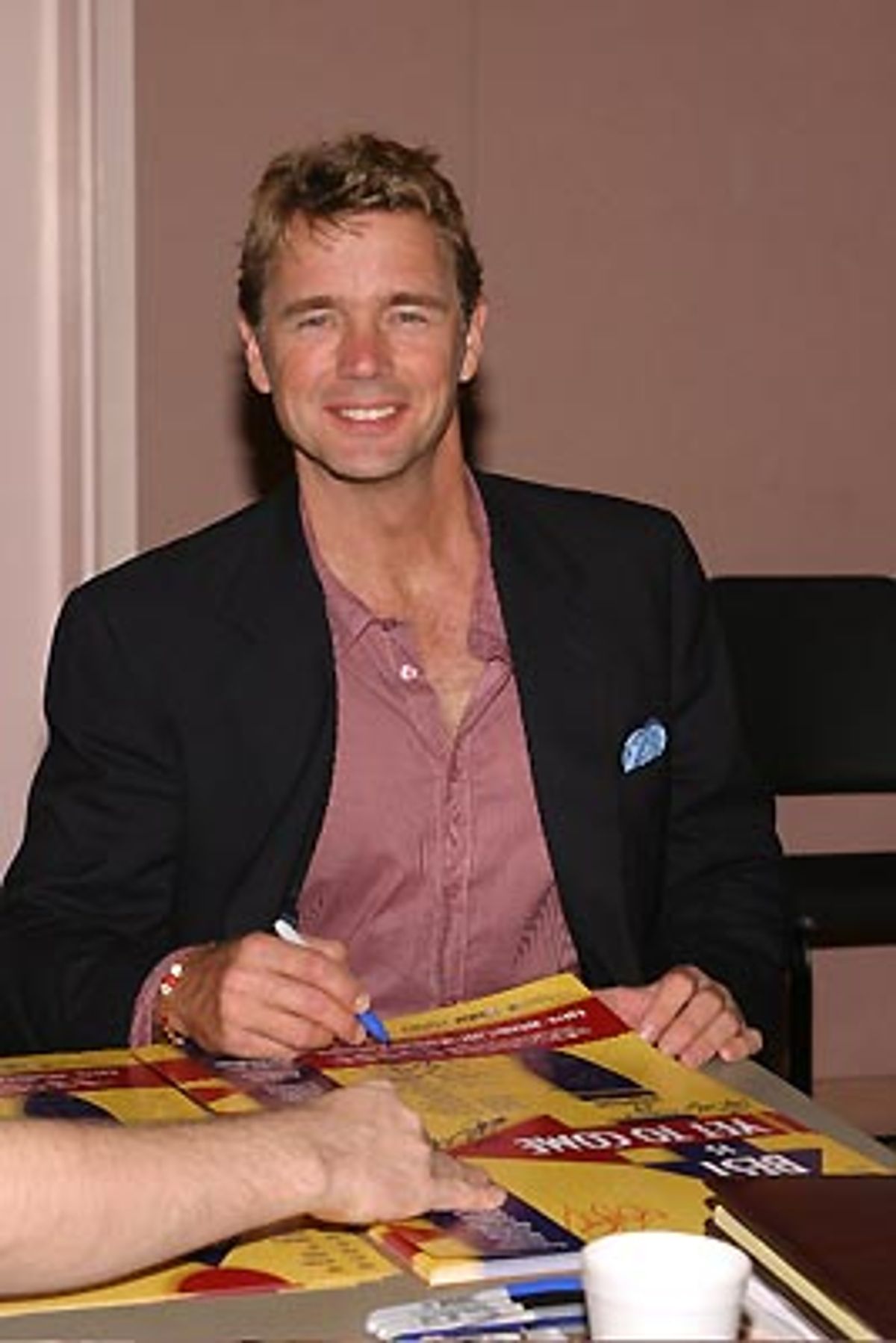 John Schneider looks up from autographing posters to give us a quick smile at 