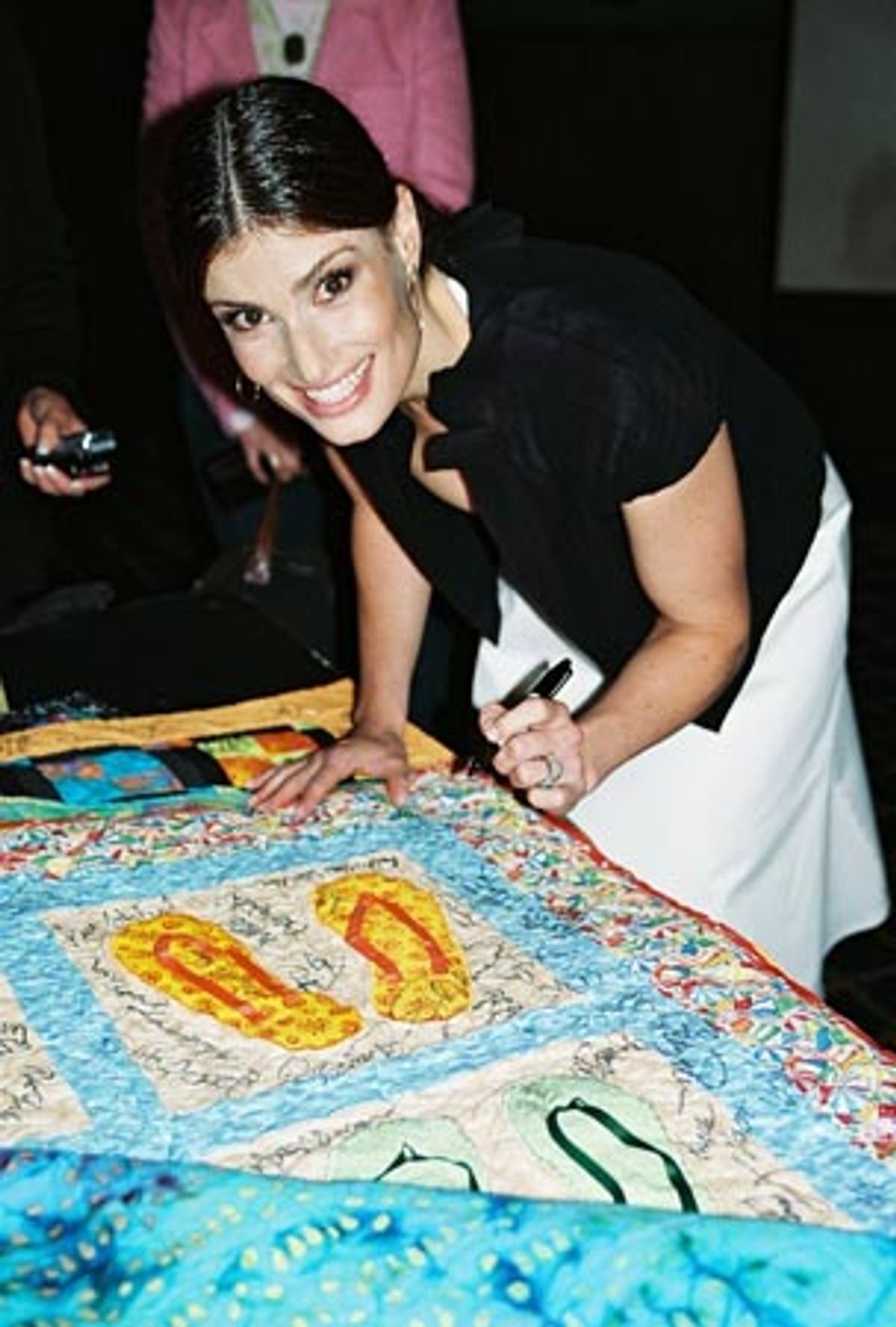 Idina Menzel signing a quilt to be auctioned off for the victims of Hurricane Katrina  at 