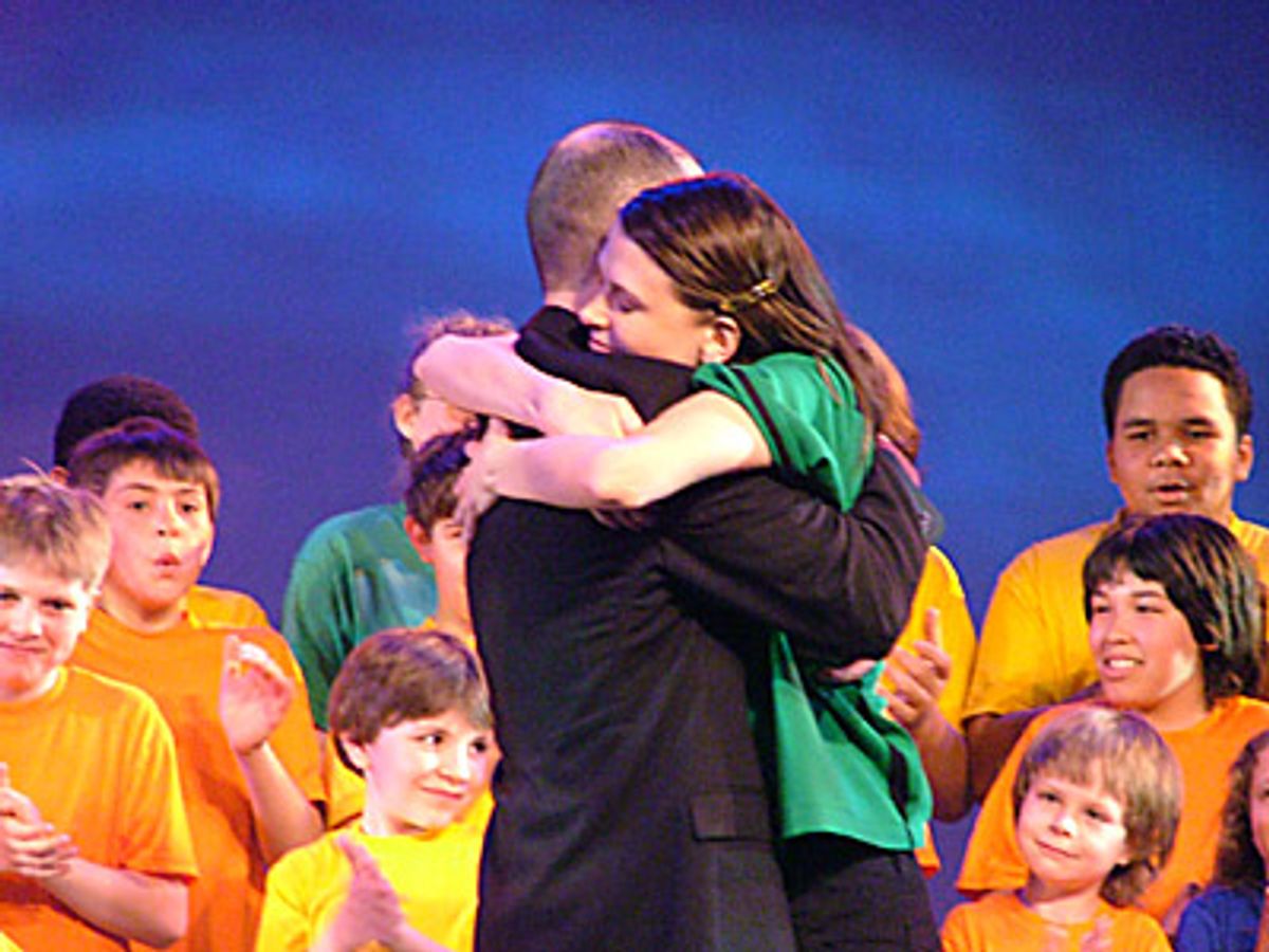 Reinaldo 'Rey-Rey' MartÃ­nez-Cubero (Founder of the Pied Piper Children's Theater NYC)
and Sutton embrace after Jamie McGonnigal shares with the audience that
the benefit raised a total of $70,091 (to date) at 