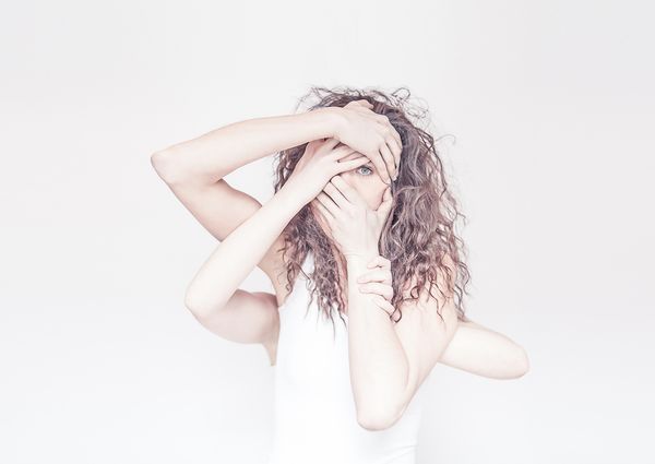 One woman stands behind another, their arms interlocked across the face of the woman in front. Norah Sadava & Amy Nostbakken - photo by Brooke Westlock 1
