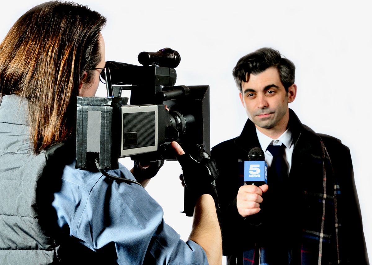 Keaton Fields as Larry the cameraman films Travis Bilenski as Phil Connors, the TV weatherman, in the musical comedy Groundhog Day: The Musical, playing at Lakewood Theatre Company, located at 368 S. 