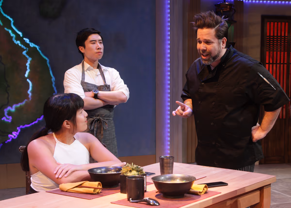 Hannah Mariah as Danielle, Dustin Vuong Nguyen as Sam, and Casey Long as Chris in the rolling world premiere of "Colonialism is Terrible, But Phở is Delicious," playing March 31 - April 30, 2023 at Better Aitken theater arts Center on the Cripe Stage. Written by Dustin H. Chinn; Directed by Oánh Nguyễn. Photo by Doug Catiller, True Image Studio. 