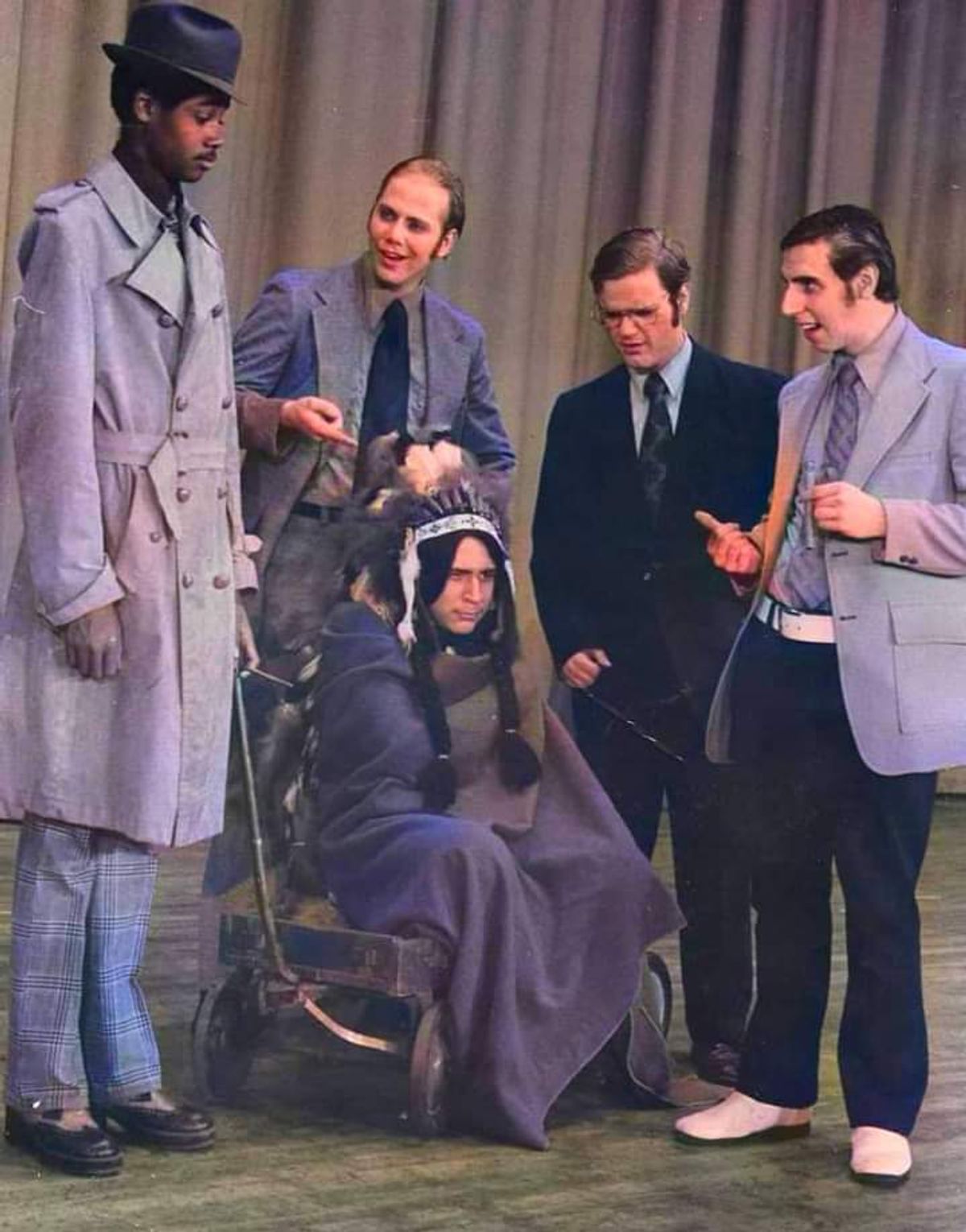 WHAT THE HELL'S A WABEENO?: Talented young actor Ignacio Torres as The Indian Chief Wabeeno ( seated center on a wagon ) provides humorous and cryptic clues to Darryl Maximilian Robinson as Detective Sam Spaced ( standing far left ) and members of the Albert G. Lane Technical High School senior staff Dave Ladner as Mr. Mazukuras, John Bliss as Mr. Pauley and Rick Crom ( standing far right  ) as Principal Norman Silber in parody composer / lyricist / and comedy scriptwriter Crom's 1975 satirical comedy / mystery review "The Maltese Wabeeno". This 1975 Production Photo is courtesy of the Albert G. Lane Technical High School Music Theatre.