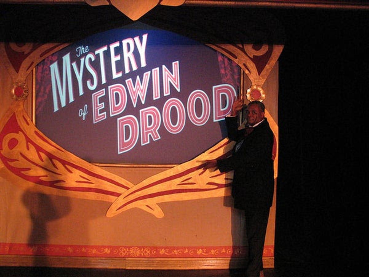 Welcome To A Killer Of A Dickens Show!: 2019 Broadwayworld Chicago Award nominee for Best Performer In A Musical or Revue Darryl Maximilian Robinson, in his dual roles of The Chairman Mr. William Cartwright and Mayor Thomas Sapsea, takes us into a musical mystery unresolved by its title source author Charles Dickens with Rupert Holmes' multi-song whodunit 'The Mystery of Edwin Drood'. Photo by Set Designer Emil Zbella. Welcome To A Killer Of A Dickens Show!: 2019 Broadwayworld Chicago Award nominee for Best Performer In A Musical or Revue Darryl Maximilian Robinson, in his dual roles of The Chairman Mr. William Cartwright and Mayor Thomas Sapsea, takes us into a musical mystery unresolved by its title source author Charles Dickens with Rupert Holmes' multi-song whodunit 'The Mystery of Edwin Drood'. Photo by Set Designer Emil Zbella.
