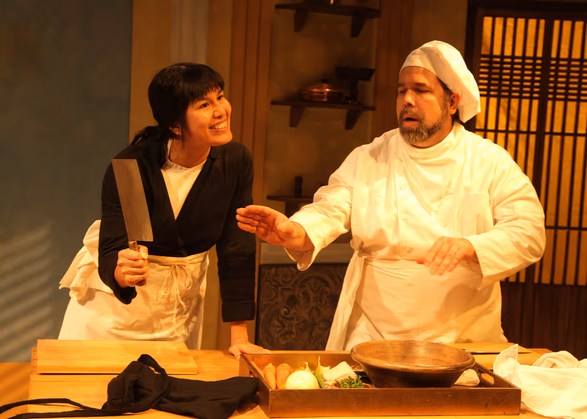 Hannah Mariah as Thúy and Casey Long as Guillaume in the rolling world premiere of "Colonialism is Terrible, But Phở is Delicious," playing March 31 - April 30, 2023 at Better Aitken theater arts Center on the Cripe Stage. Written by Dustin H. Chinn; Directed by Oánh Nguyễn. Photo by Doug Catiller, True Image Studio. 