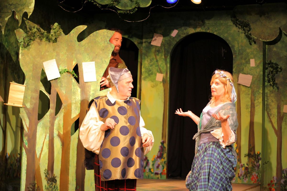 Even a fool like Touchstone (Ken Knight) can find love in the forest with Audrey (Andrea Stradling) as Jaques (Jonah Goger) eavesdrops.