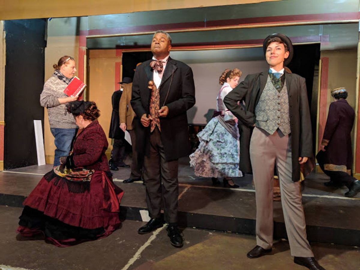 The Director of The Show Directs The Photo Shoot!: Skilled veteran director and musical director Robert-Eric West ( left with notes ) tells the show's Principal Cast ( including Darryl Maximilian Robinson as The Chairman Mr. William Cartwright at center, and Sarah Myers as Edwin Drood at right ) what he wants conveyed during the publicity photo session for the 2018 Saint Sebastian Players of Chicago Revival of Rupert Holmes' 'The Mystery of Edwin Drood'. Photo by Eryn Walanka. The Director of The Show Directs The Photo Shoot!: Skilled veteran director and musical director Robert-Eric West ( left with notes ) tells the show's Principal Cast ( including Darryl Maximilian Robinson as The Chairman Mr. William Cartwright at center, and Sarah Myers as Edwin Drood at right ) what he wants conveyed during the publicity photo session for the 2018 Saint Sebastian Players of Chicago Revival of Rupert Holmes' 'The Mystery of Edwin Drood'. Photo by Eryn Walanka.