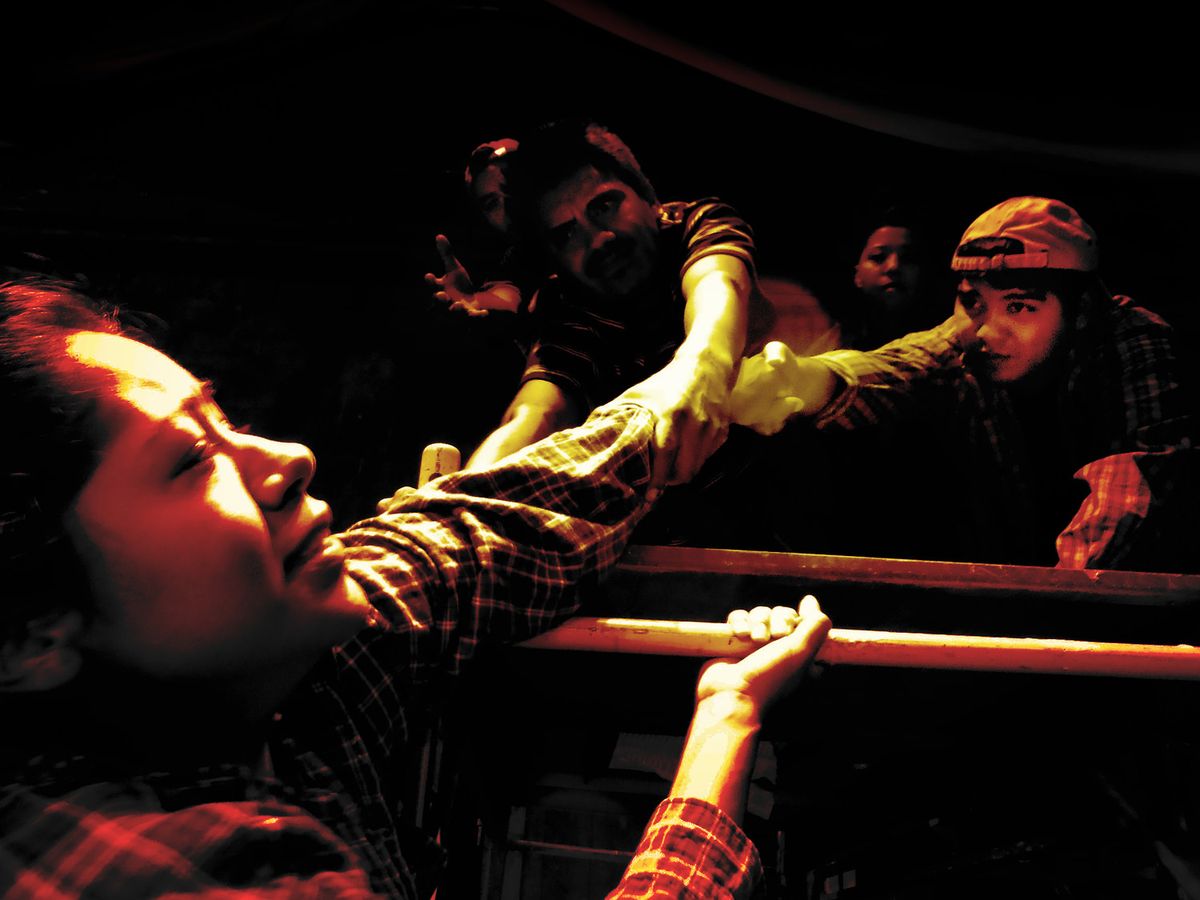 Migrants helping other migrant from falling off the train. 