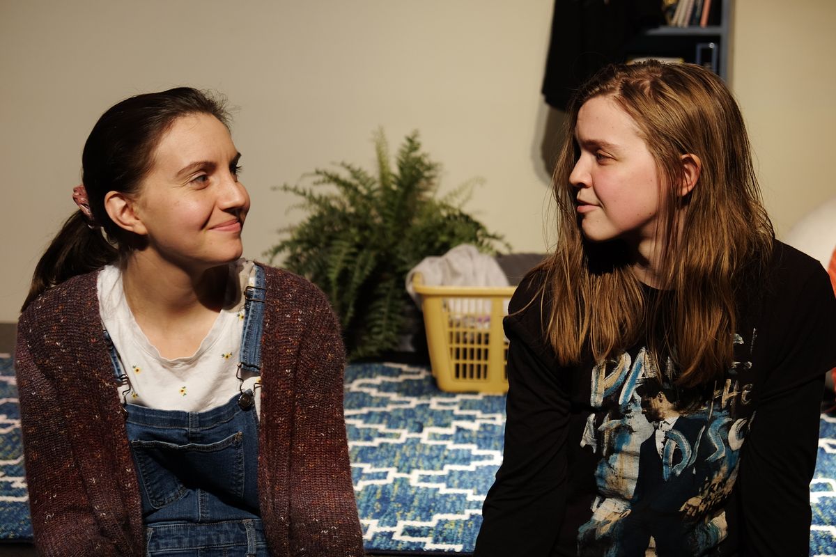 Teen Mak, played by Elizabeth Eby, and Adult Mak, played by playwright and actor Makayla Baker Paxton, looks at each other with understanding. 
