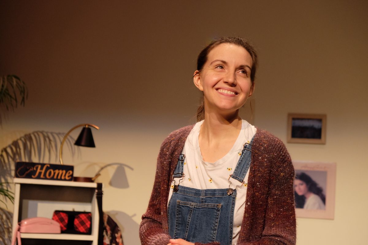 Adult Mak, played by playwright and actor MaKayla Baker Paxton, looks up and smiles off camera