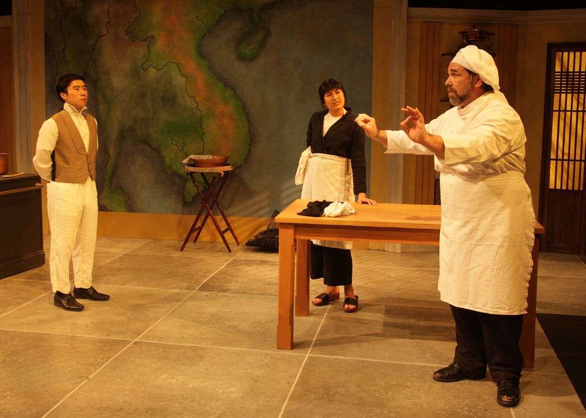 Dustin Vuong Ngyuen as Nguyễn, Casey Long as Guillaume, and Hannah Mariah as Thúy in the rolling world premiere of "Colonialism is Terrible, But Phở is Delicious," playing March 31 - April 30, 2023 at Better Aitken theater arts Center on the Cripe Stage. Written by Dustin H. Chinn; Directed by Oánh Nguyễn. Photo by Doug Catiller, True Image Studio. 