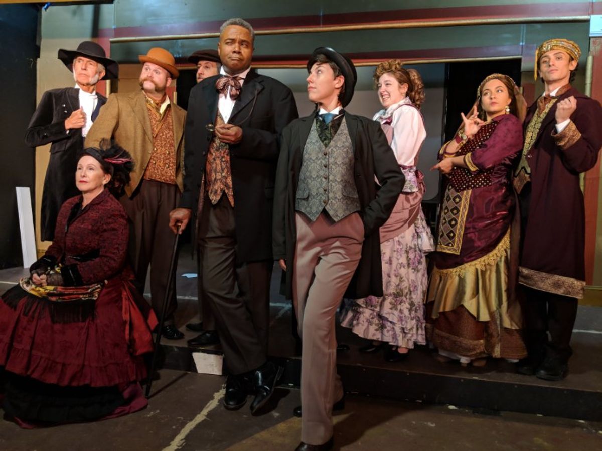 Who Would Want To Murder Such A Fine Young Man?: Surrounded by Multiple Suspects, Darryl Maximilian Robinson as The Chairman Mr. William Cartwright ( center left ) ponders who might have a reason to kill Sarah Myers as Edwin Drood ( center right ) in the 2018 Saint Sebastian Players of Chicago revival of Rupert Holmes' Tony Award-winning Best Musical Whodunit 'The Mystery of Edwin Drood'. Photo by Eryn Walanka. Who Would Want To Murder Such A Fine Young Man?: Surrounded by Multiple Suspects, Darryl Maximilian Robinson as The Chairman Mr. William Cartwright ( center left ) ponders who might have a reason to kill Sarah Myers as Edwin Drood ( center right ) in the 2018 Saint Sebastian Players of Chicago revival of Rupert Holmes' Tony Award-winning Best Musical Whodunit 'The Mystery of Edwin Drood'. Photo by Eryn Walanka.