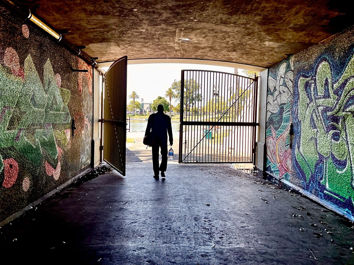 Exploring MacArthur Park: Seeking the right spot to shoot a preview video of his new recording of Edgar Allan Poe's classic poem 'The Conqueror Worm', veteran stage actor and play director Darryl Maximilian Robinson takes a stroll through a highly decorated tunnel near the Levitt Pavilion. Photo by Danny Belrose Exploring MacArthur Park: Seeking the right spot to shoot a preview video of his new recording of Edgar Allan Poe's classic poem 'The Conqueror Worm', veteran stage actor and play director Darryl Maximilian Robinson takes a stroll through a highly decorated tunnel near the Levitt Pavilion. Photo by Danny Belrose
