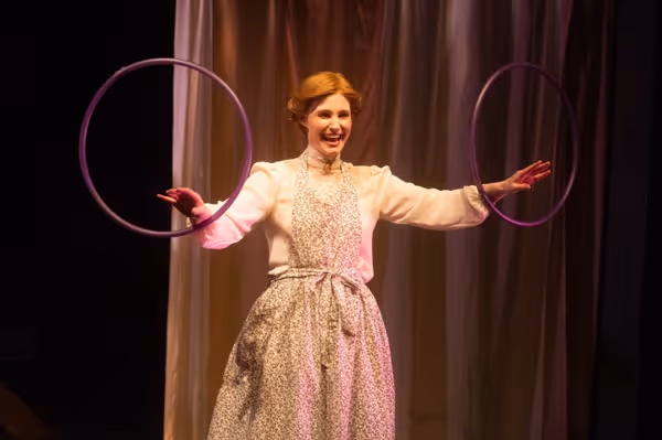 In this still, Meg March (Amy Rene Byrne) represents her trouble making current jam by twirling two hoolah hoops on her wrists. This retelling of Little Women makes it ambiguous whether we are witness 18