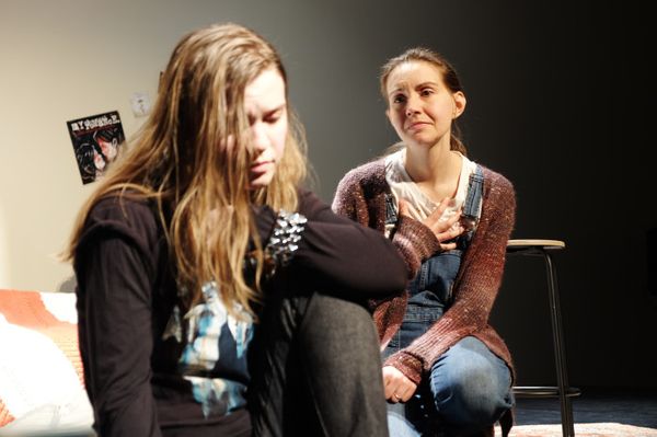 Teen Mak, played by actor Elizabeth Eby (left) looks down, distraught as Adult Mak, played by playwright and actor Makayla Baker Paxton (right) looks longingly at her with her hand on her heart. 1