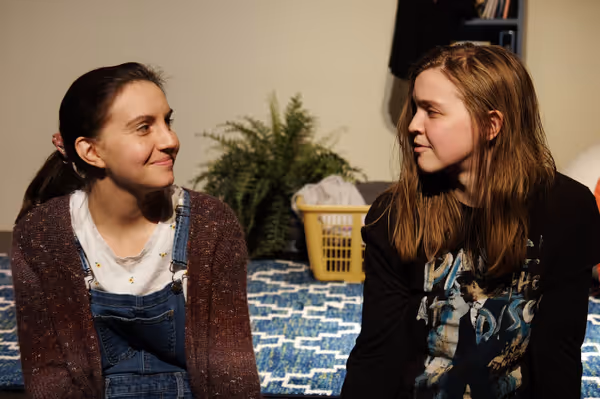 Teen Mak, played by Elizabeth Eby, and Adult Mak, played by playwright and actor Makayla Baker Paxton, looks at each other with understanding.  2