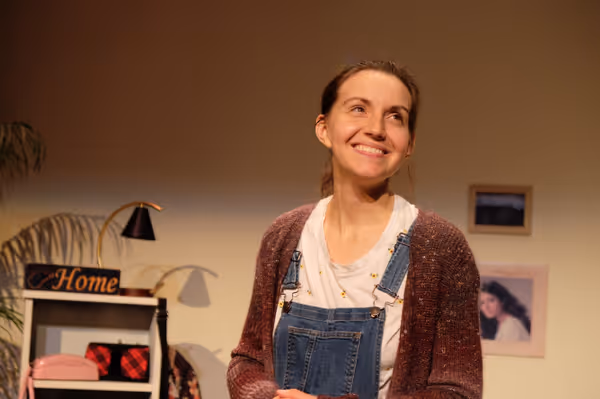 Adult Mak, played by playwright and actor MaKayla Baker Paxton, looks up and smiles off camera 3