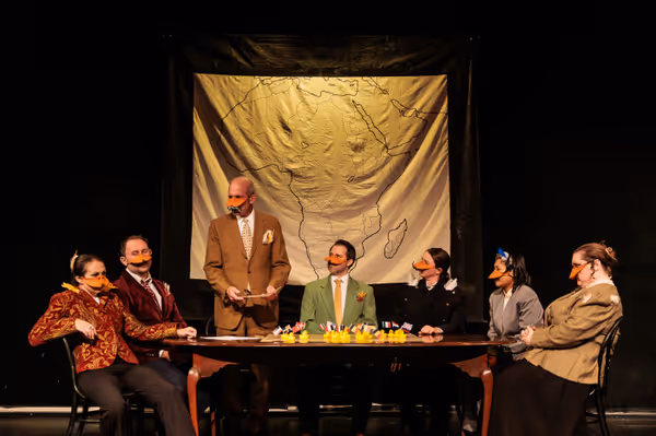 The delegates (l-r seated Allison McCall, Ryland Garnett, Nate Speckman, Madison Shmalo, Chris Say, and Hollie Pryor) listen as Otto von Bisquack (Gary Penn, standing) prepares them all for a vote in Heart of Duckness by A.J. Ditty. Photo by Kat Moraros Photography. 17