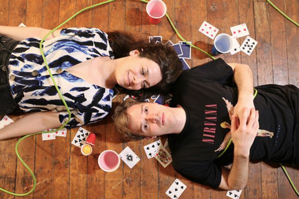 Photo by: Calvin Petersen and Will King
Featuring (L to R): Courtney Keir, Will King
Alt text: A couple lie on the ground of an old floor in a romantic but concerning pose. They are
surrounded by junk, party cups, and electrical cords. 1