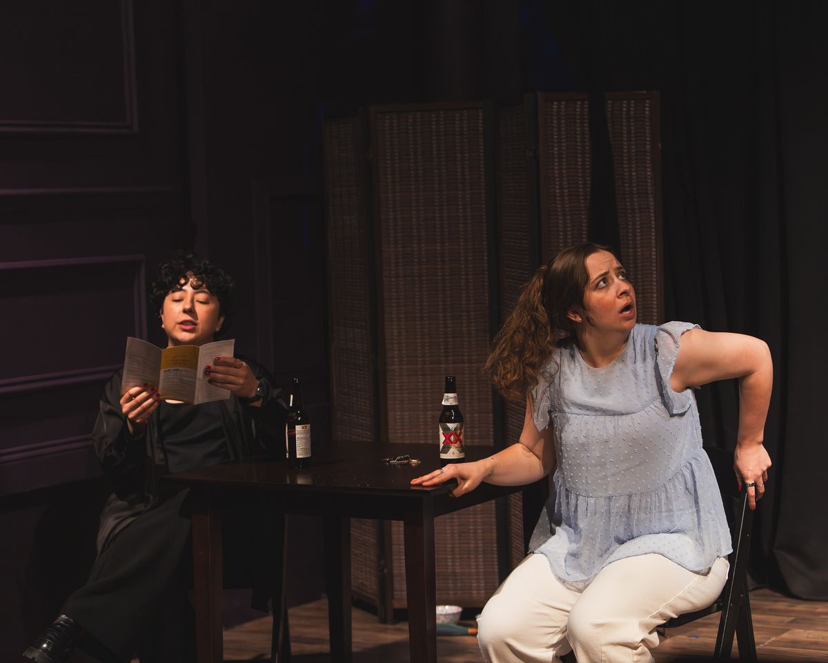Melanie Santos Cordero as Callie and Bridgette Dove as Sarah share a moment as a neighbor s noise interrupts, menu in hand. Photo by MCP Photo. Melanie Santos Cordero as Callie and Bridgette Dove as Sarah share a moment as a neighbor s noise interrupts, menu in hand. Photo by MCP Photo.