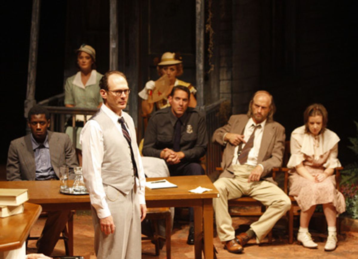 David Bishins (standing) plays Atticus Finch, [seated in the foreground] are Sean Phillips (Tom Robinson), David Drummond (Heck Tate), Russell Hodgkinson (Bob Ewell) and Liz Morton (Mayella Ewell), [seated at rear] Patti Cohenour (Miss Maudie) and Lori La at 
