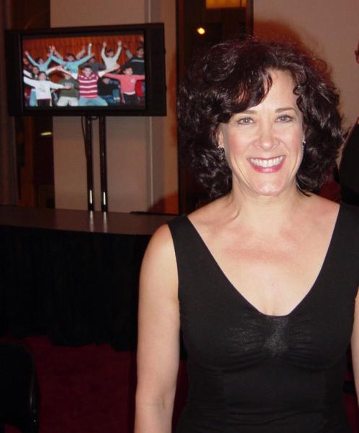 Karen Ziemba, a past recipient of the Beacon Award, stands in front of a screen displaying a picture of an Inside Broadway activity. She presented the award to Neuwirth, with whom sheâ€™s danced Chicagoâ€™s â€œHot Honey Ragâ€ at the Clinton White House a at Broadway Beacon Awards