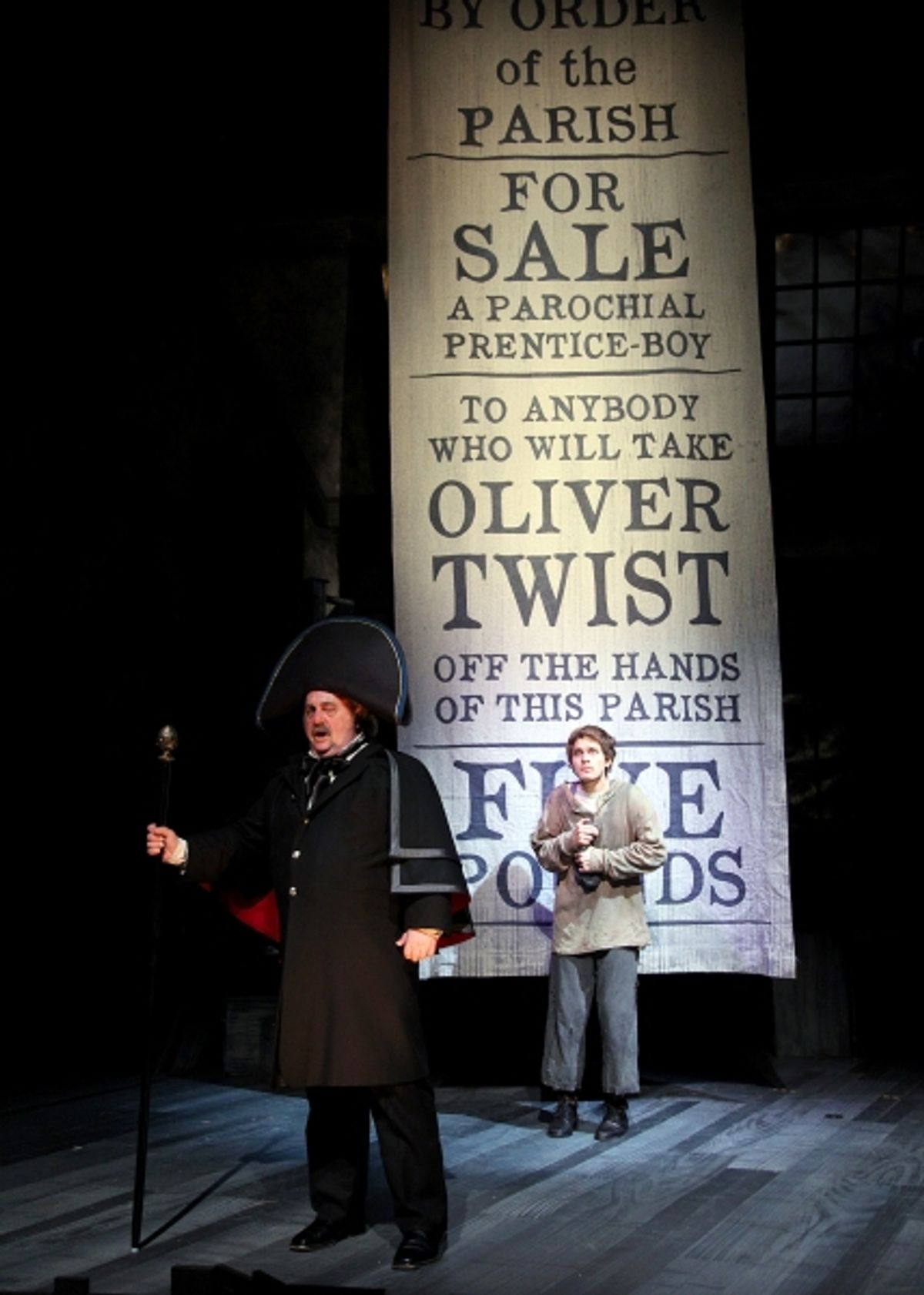 Eric Hoffmann as Mr. Bumble, a parish beadle and (rear) Quentin McCuiston as Oliver Twist
 at 