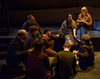 Liesel (Rae Gray) reads to a group huddled in a bomb shelter Photo