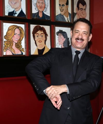 Tom Hanks with wife Rita Wilson caricature behind him Photo