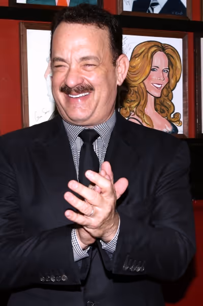 Tom Hanks with wife Rita Wilson caricature behind him Photo