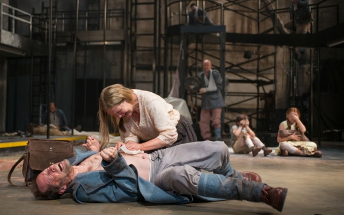 Beatriz (ensemble member Joan Allen, center) attempts to remove a bullet from a soldier (ensemble member Tim Hopper) at 