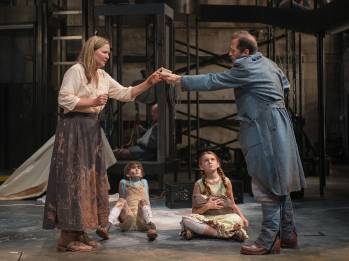 Beatriz (ensemble member Joan Allen, left) is paid to help a soldier (ensemble member Tim Hopper, right) as The Boy (Daniel Pass) and The Girl (Emma Gordon) look on at 