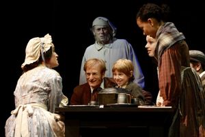 Center: Nick Corley (Bob Cratchit) and Hunter Metnick (Tiny Tim). Background: Steven  Photo