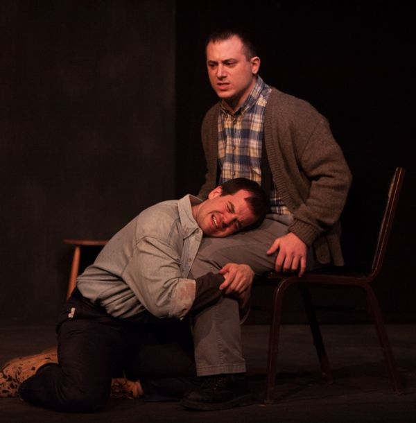 Katurian (Tom Mazzarella, kneeling) seeks comfort after his interrogation from his br Photo