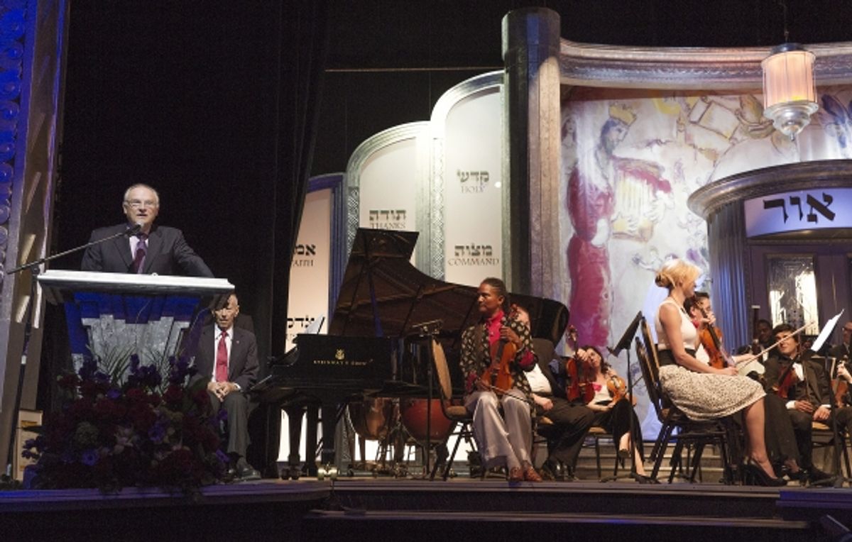 Event Emcee Bill Smitrovich at podium at An International Evening of  Music and Remembrance celebrating the Voices of Holocaust Survivors through a   performance of Sharon FarberÃ¢â‚¬â„¢s Bestemming: Concerto for Cello, Orchestra and   Narration inspired  at 