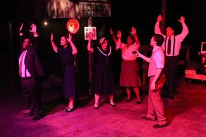 Clyde (Matt Pentecost, in front) holds up a shopkeeper in ''God''s Arms Are Always Op Photo