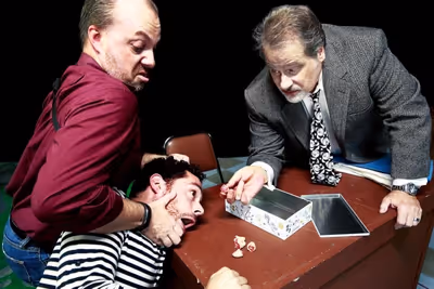 The detectives (Trevor B. Cone, Scott Holmes) show Katurian (Aaron Echegaray) the evi Photo