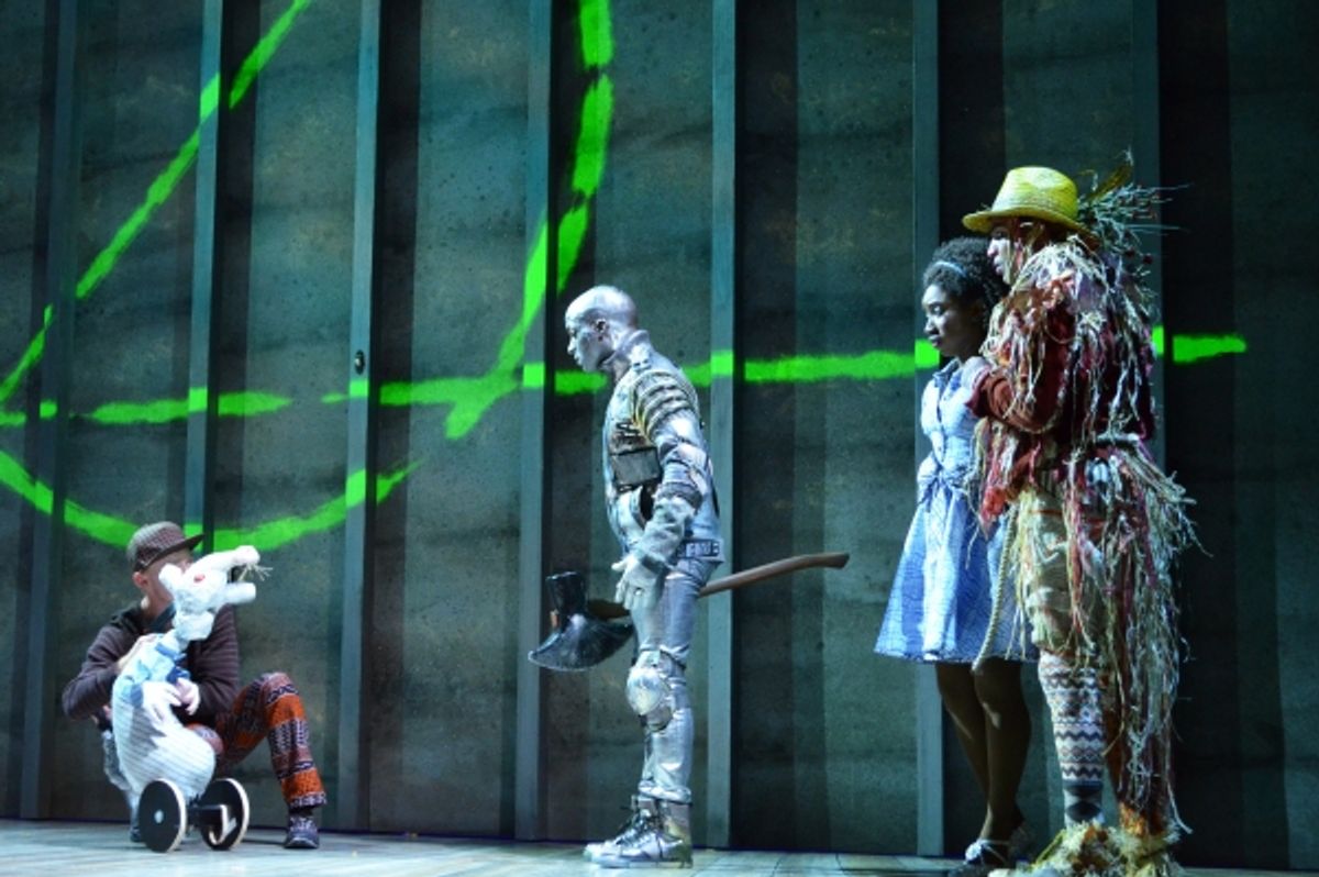 A mouse (puppet operated by Austin Carroll) addresses the Tinman (Tyrick Wiltez Jones), Dorothy (Destinee Rea) and the Scarecrow (David LaMarr) outside the gates of Oz at 