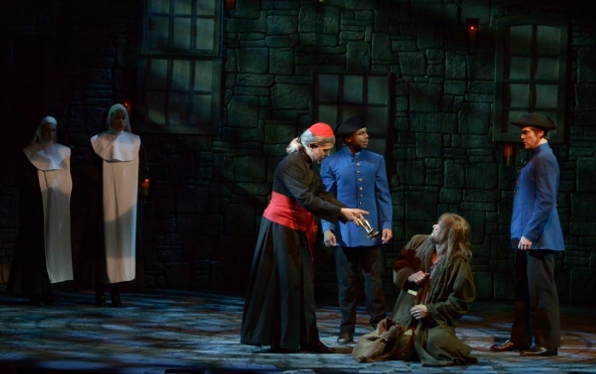 The Bishop (Gabriel Zenone) offers a gift to Valjean (Gregg Goodbrod), seated, as the constables (Cornelius Davis and Chris Crawford), right, and nuns (Emily Rynasko and Anna Kelly), left, look on at 