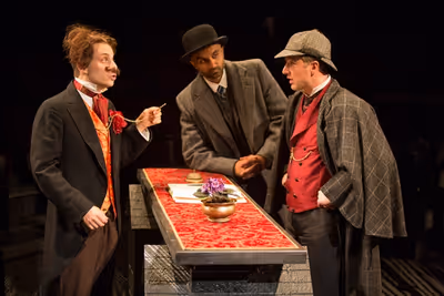 Blake Segal as Castilian Desk Clerk, Usman Ally as Doctor Watson, and Euan Morton as  Photo