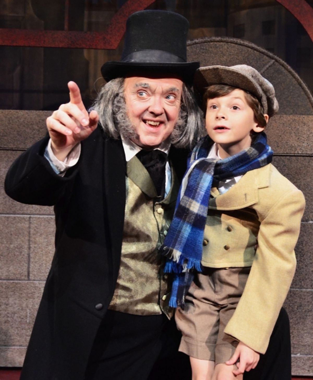 A newly-reformed Ebenezer Scrooge (Eddie Curry) celebrates Christmas with Tiny Tim (Holland Barnes) at 