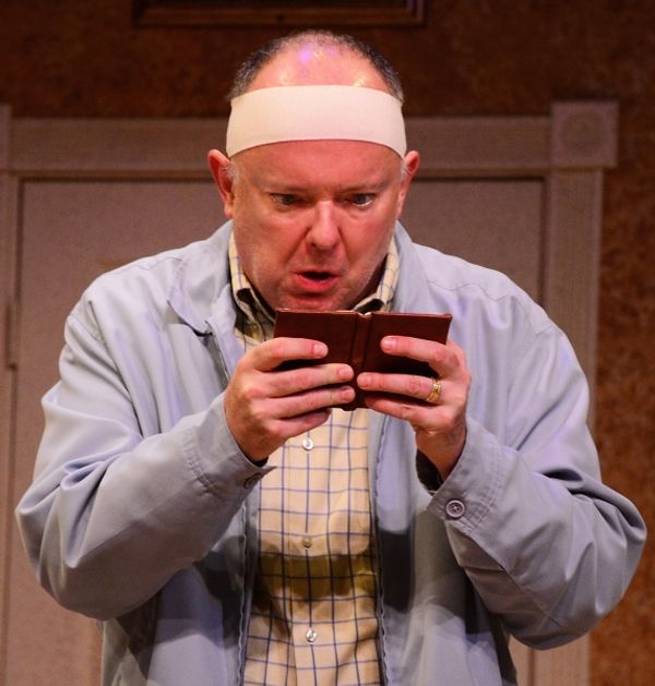 John Smith (Eddie Curry) frantically checks his schedule. Photo