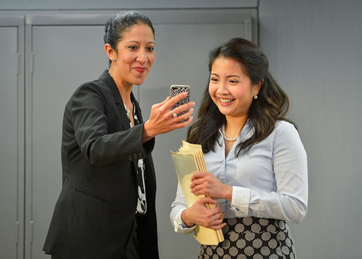 Charlene (Sarah Nina Hayon) and Vivan (Kristin Villanueva) in the break room, looking at pictures of Charlene's kids. at 