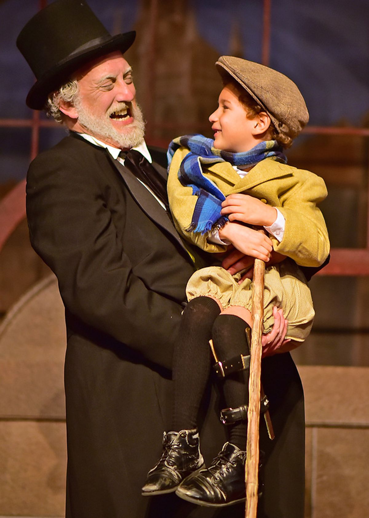 Ebenezer Scrooge (Jeff Stockberger) lifts Tiny Tim (Ashton Curry) at 