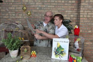 Chester Nurdiger (Ed Jones) shows Officer Frankie Spinelli (Chazie Bly) how to care for his new parrot in a publicity image for Hell in a Handbag Productions’ comedy THE ARTIFICIAL JUNGLE. @ BroadwayWorld Chester Nurdiger (Ed Jones) shows Officer Frankie Spinelli (Chazie Bly) how to care f Photo