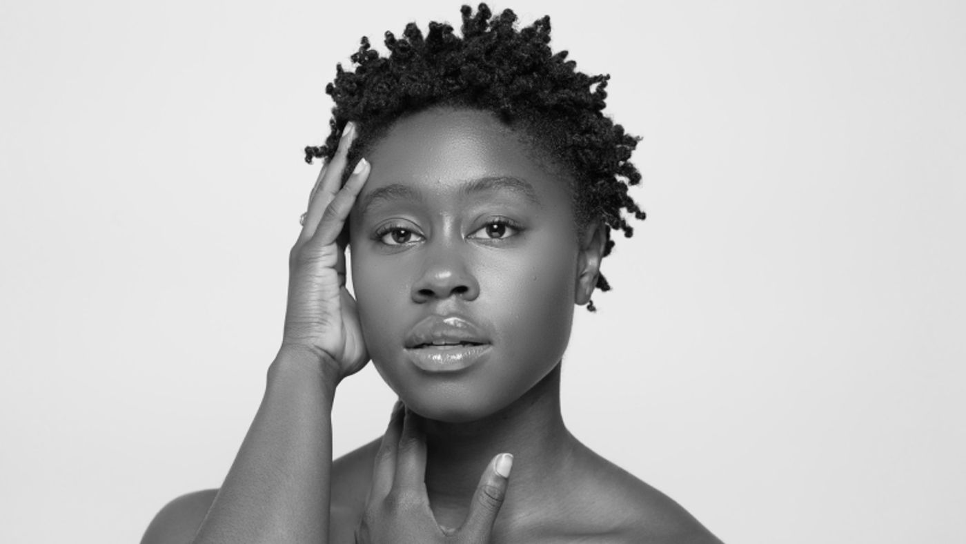 Alvin Ailey American Dance Theater's Ashley Kaylynn Green looking into the camera, hands placed tenderly and thoughtfully against her neck and one side of her head