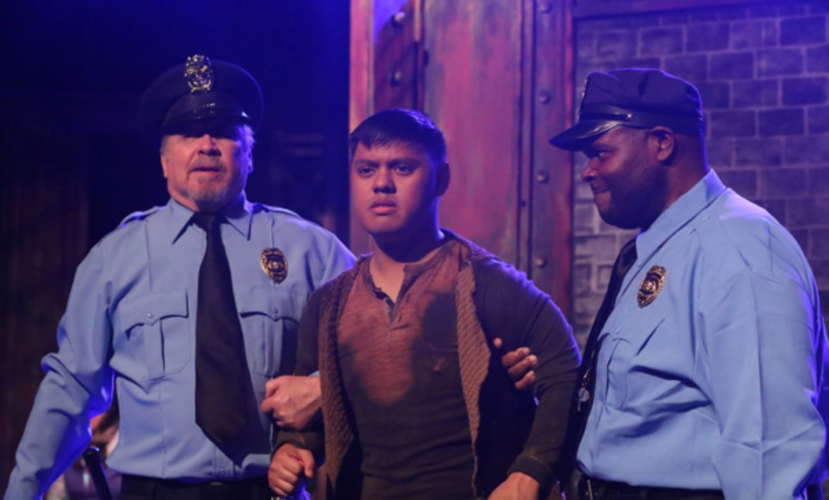 Officers Lockstock (Kent Coffel, left) and Barrel (Marshall Jennings, right) take custody of Bobby Strong (Kevin Corpuz, center), in New Line Theatre's URINETOWN, 2022. Photo credit: Jill Ritter Lindberg.
 at 