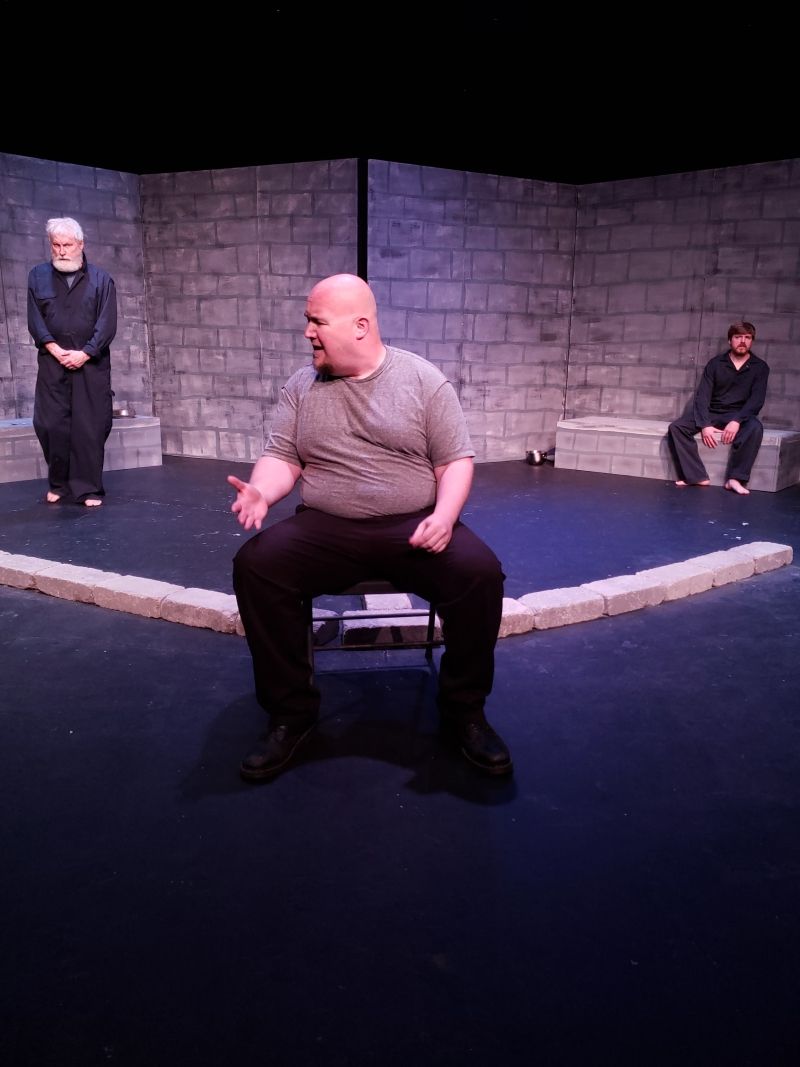 Mr. Smeija (Mike Adams) chats with the prisoners. 