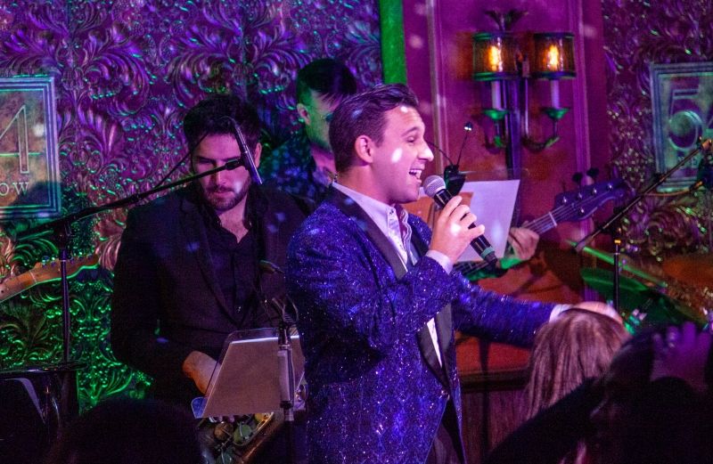 Nicolas King sings into a handheld mic, with his left hand on the mic stand.