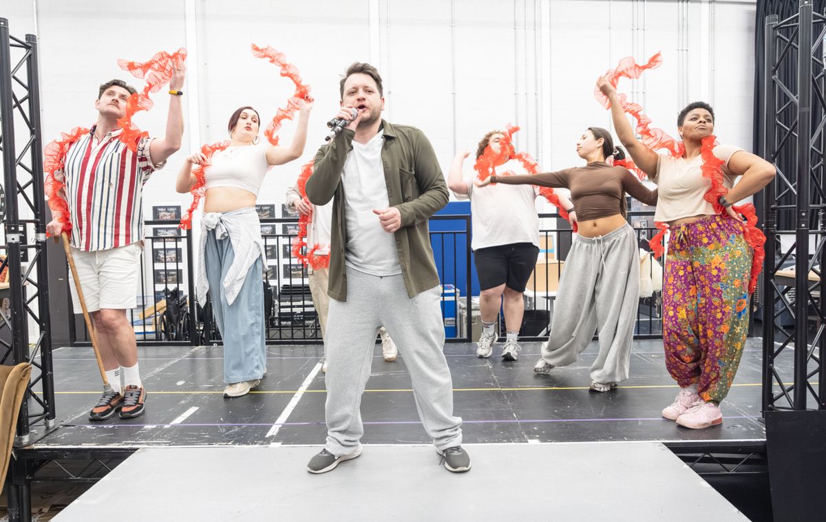 Sam Lupton (Centre) & The cast in rehearsals for BANK OF DAVE, credit Marc Brenner at 